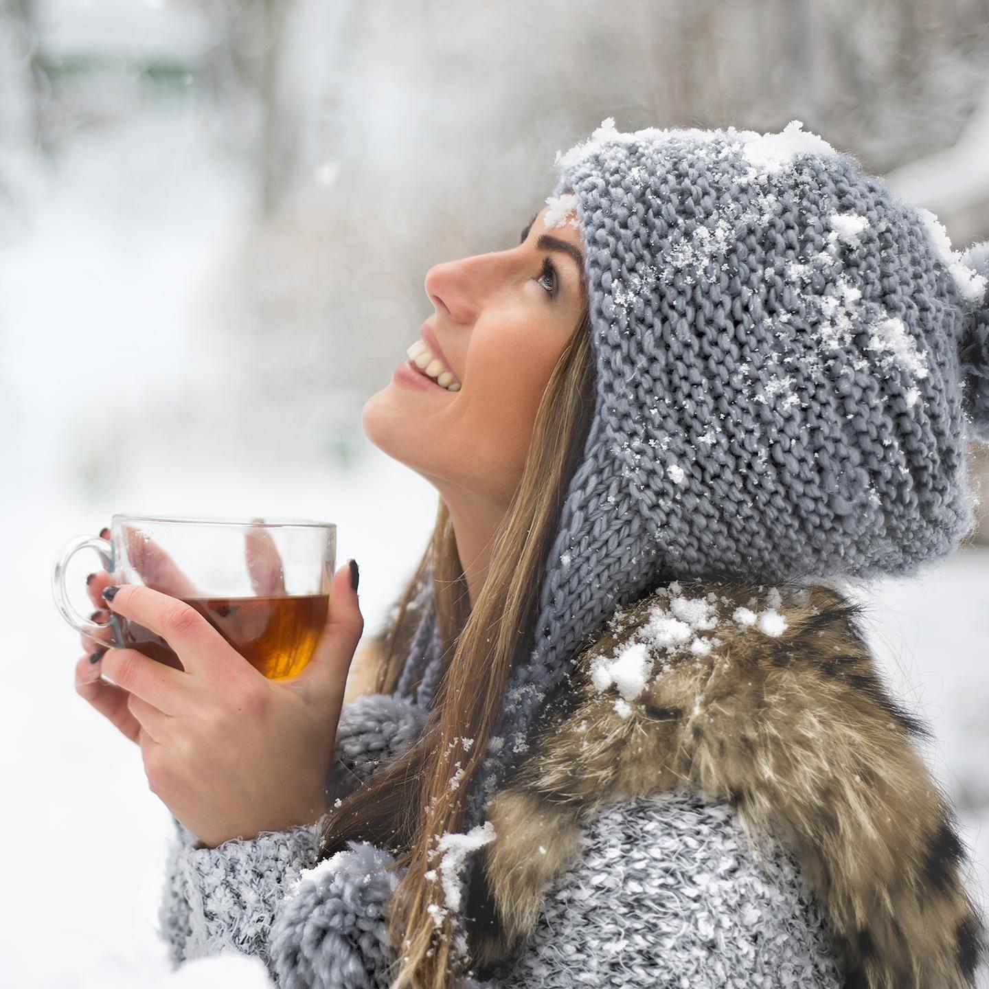 Une femme boit une tasse de thé sous la neige