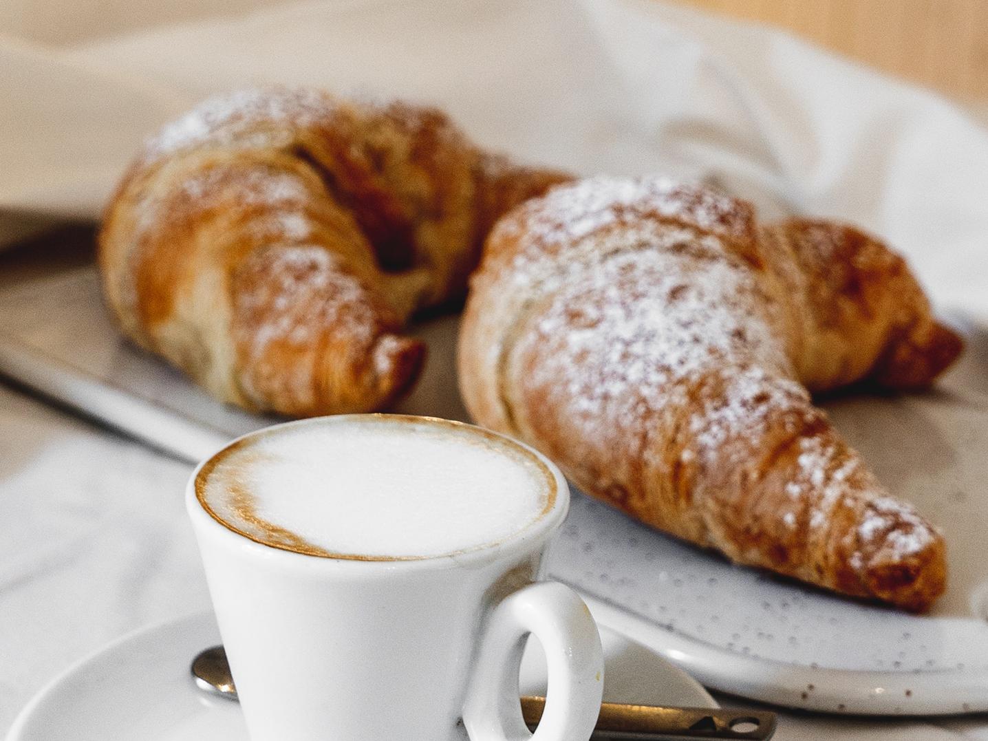 Un café est des croissants sont posés sur une table