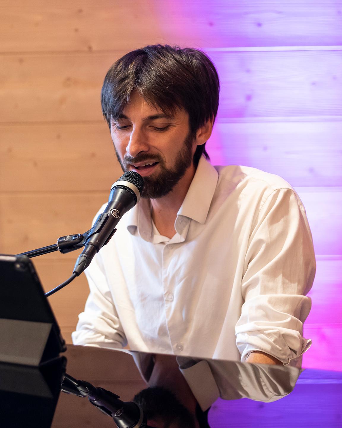 Un homme est en train de jouer du piano et de chanter en même temps au M'bar