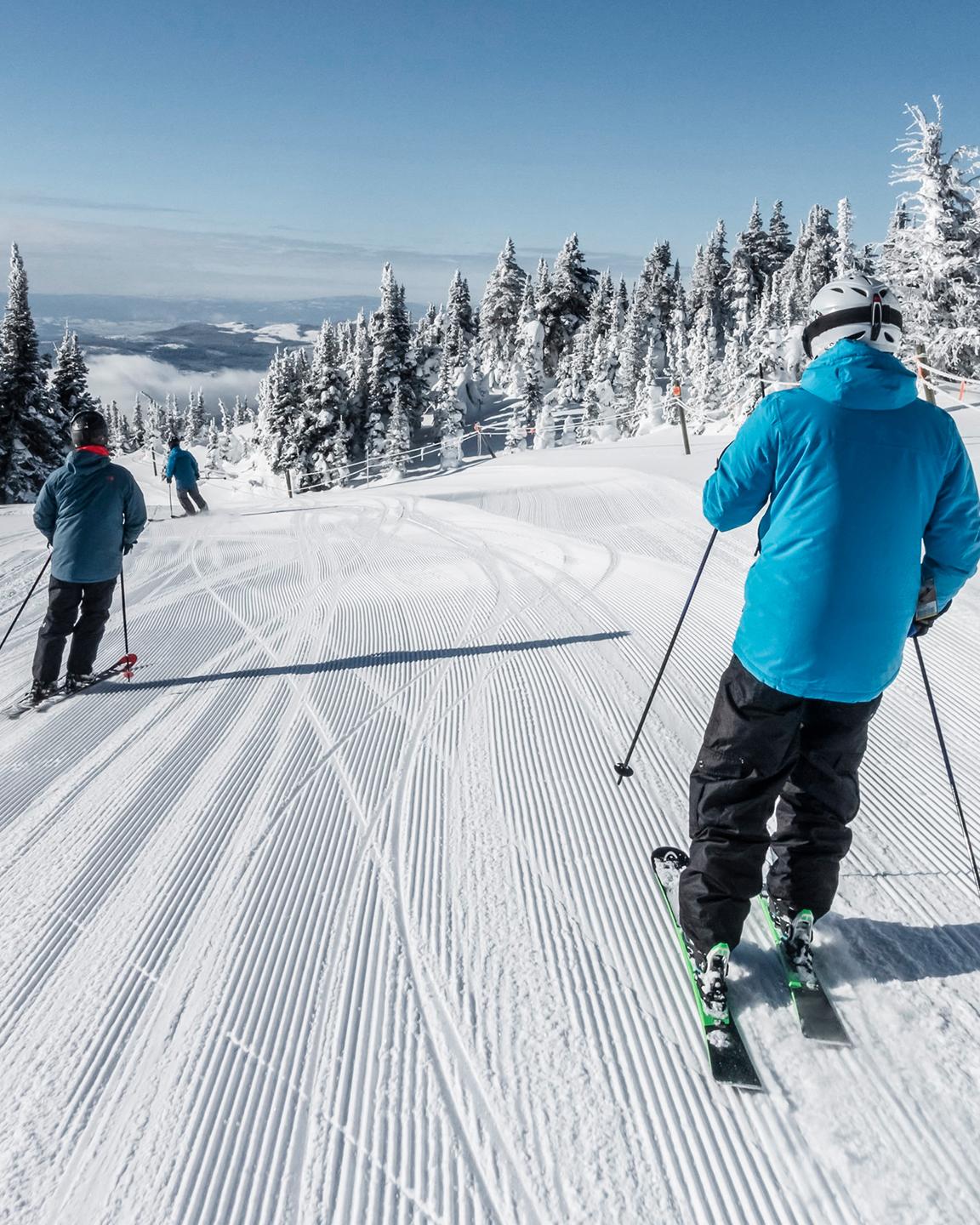 Trois personnes sont en train de descendre une piste à ski