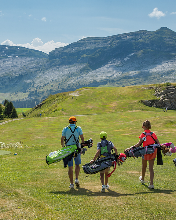 Une famille entrain de porter leurs clubs de golf sur le terrain de Flaine