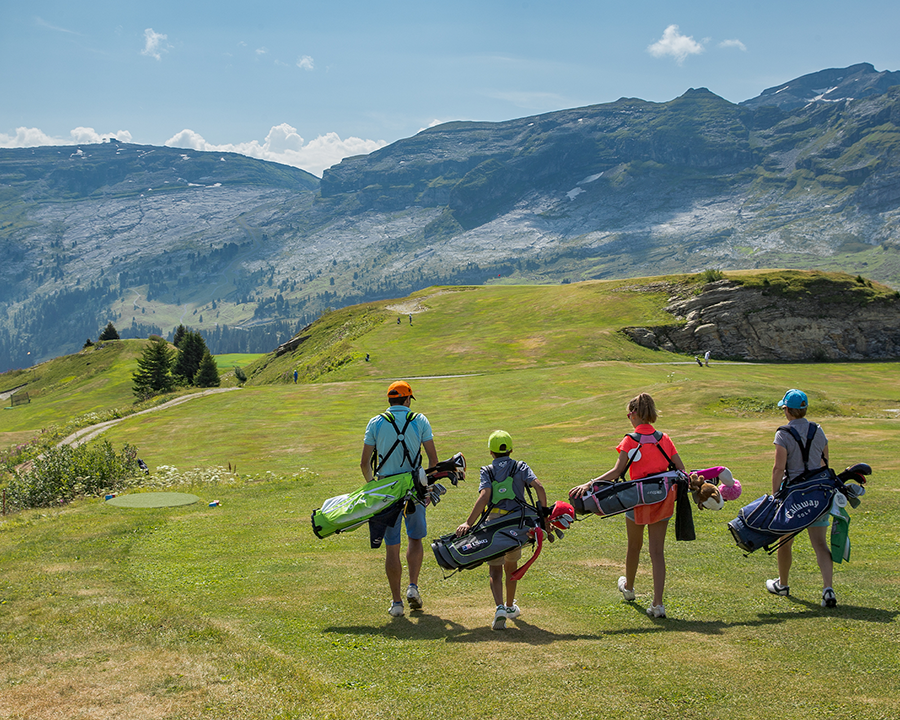 Une famille entrain de porter leurs clubs de golf sur le terrain de Flaine