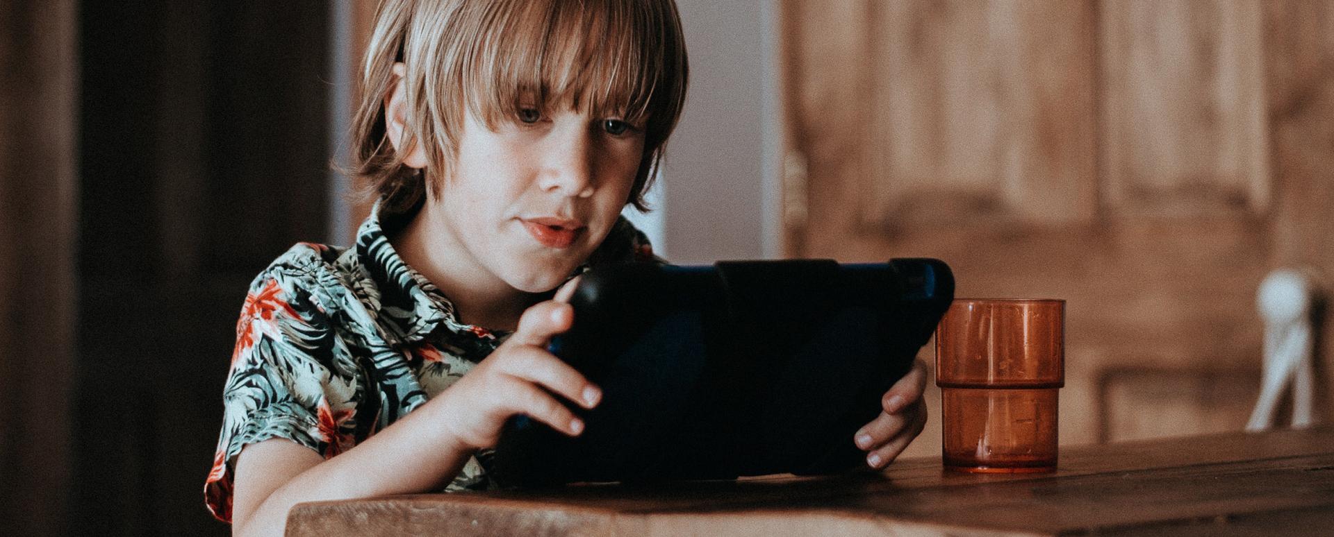 Un enfant est en train de jouer avec une tablette devant un comptoir